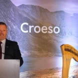 Health Secretary stood in front of welcome boards 