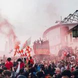 Wrexham football players on a coach travelling past a crowd of people.