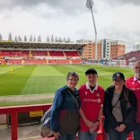 Four people wearing Welsh football shirts standing inside the stadium