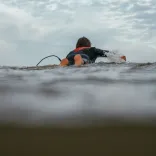 A person lying on a surf board in the sea.