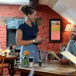 A server in a pub tends to two patrons sitting at a table