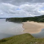 A scenic shot of a beautiful sandy bay with green mountains lining the sea