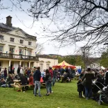 Crowds of people standing outside a large white building at the festival.