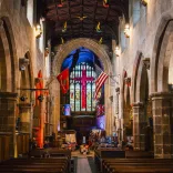 The inside of a beautiful old Welsh church showing an American flag hanging from the rafters 