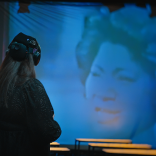 A person wearing headphones watching a show on screen