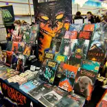 A comic convention stall displaying horror comics and graphic novels by Joseph Oliveira of Afterlight Comics.