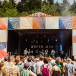 Musicians playing on a stage at the festival with a crowd of people.