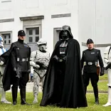 Star Wars characters, including Darth Vader and Stormtroopers, posing outside a white building.