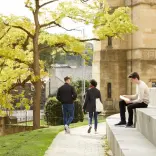 Two people walking and one sat on steps Bangor University