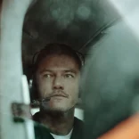 Luke Evans en pequeño avión con auriculares, listo para despegar