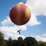 Ein pfirsichfarbener Ballon mit einem Künstler darunter