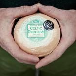 Nahaufnahme zweier Hände, die einen Laib des Celtic Promise-Käse halten.