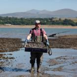 Shaun Krijnen of Menai Oysters standing with a crate of mussels