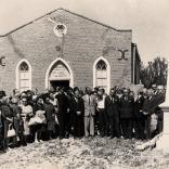 « Groupe de quatre personnes debout devant un mémorial, la chapelle Moriah ».