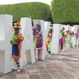 Gente vestida de colores vivos entre grandes letras del Hay Festival.