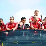 El equipo de fútbol de Gales en la parte superior de su autobús turístico saludando a la multitud debajo.