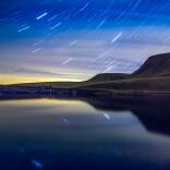  山々と星空を背景にした夜の湖の写真