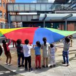 A group of children playing with a parachute.