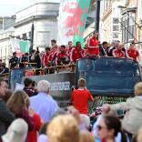 The Wales football team on top of their tour bus waving at crowds below.