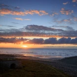 Un coucher de soleil pittoresque et vif sur une étendue de plage et de littoral.