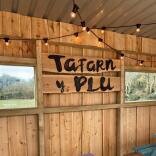 Inside a wooden garden shelter with 'Tafarn y Plu' written on a sign.