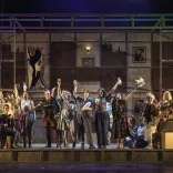 The cast of a large opera production performing on stage