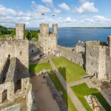 Una imagen del castillo de Caernarfon, mostrando el césped interior del castillo con el mar de fondo.