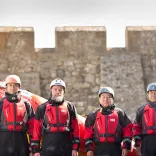 Quatre personnes debout devant un mur en pierre.