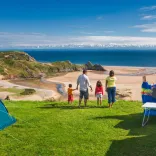 A family of four at a campsite looking over a beach and sea