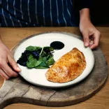 A beautifully presented plate with a Welsh oggie (pasty) and salad, on a wooden board